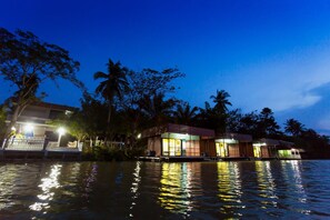 A waterfront property with multiple buildings, a dock, and palm trees. - The Neenlawat Riverside (Phunphin)