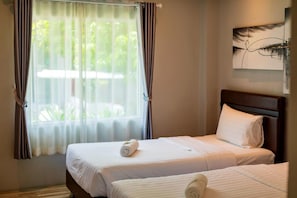 Habitació d'hotel amb dos llits, una finestra amb cortines i un quadre a la paret.