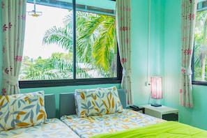 A bedroom with a bed, pillows, a nightstand, a lamp, and curtains. - The Neenlawat Riverside (Phunphin)