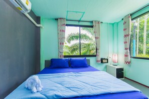 A room with a bed, a window with curtains, a bedside table with a lamp, and an air conditioning unit. - The Neenlawat Riverside (Phunphin)