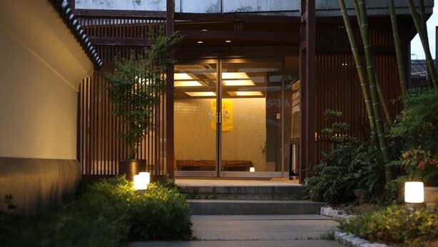A traditional Japanese building with a wooden exterior, a tiled entrance, and a pathway leading to the door. - Konpira Onsen Kashikiri Yunoyado Kotone (Kotohira)