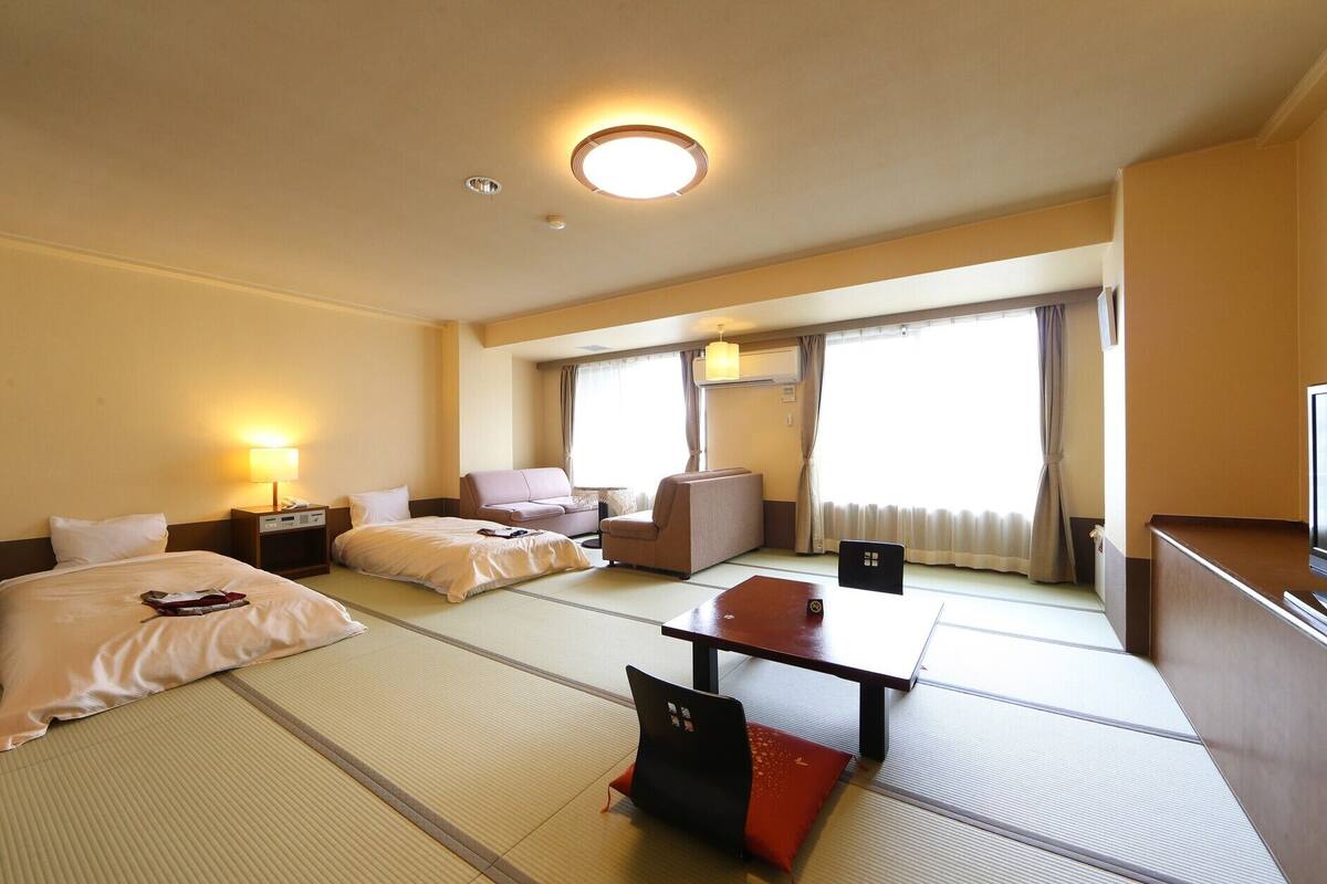 Ein Hotelzimmer mit Bett, einer Couch, einem Esstisch und einem Fernseher.