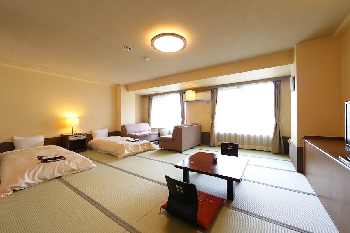 Una habitación de hotel con cama, sofá, mesa de comedor y televisor.