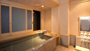 A spa room with a hot tub, a small seating area, and a mirror. - Konpira Onsen Kashikiri Yunoyado Kotone (Kotohira)