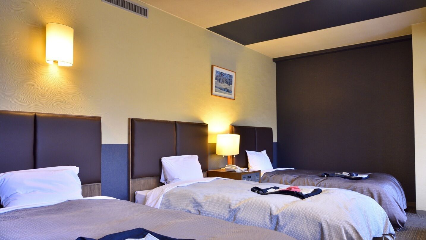 Una habitación de hotel con dos camas, una mesita de noche con una lámpara y un cuadro enmarcado en la pared.