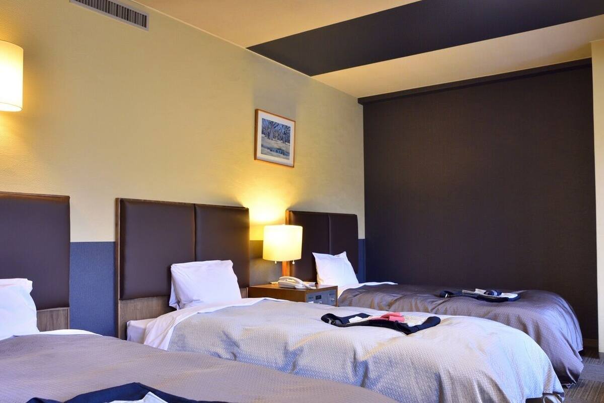 Ein Hotelzimmer mit zwei Betten, einem Nachttisch mit Lampe und einem gerahmten Bild an der Wand.