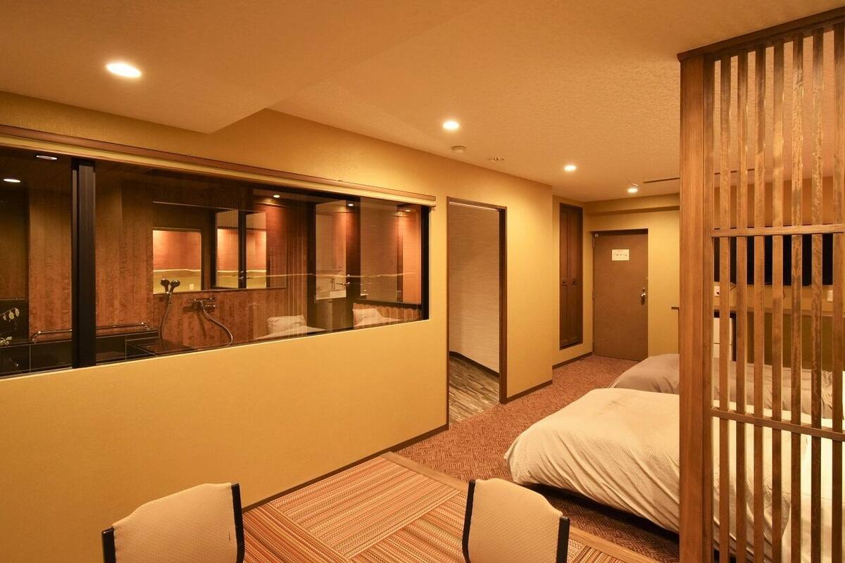 Ein Hotelzimmer mit einem großen Spiegel, zwei Betten, einer Holzvertäfelung und einem Badezimmer mit Dusche.