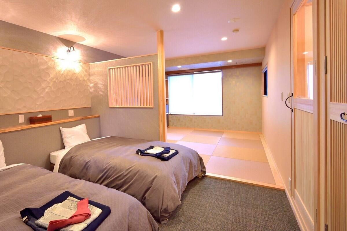Ein Hotelzimmer mit zwei Betten, einem großen Fenster und einer Wandleuchte.