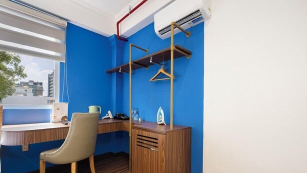 Una habitación con pared azul, un escritorio de madera, una silla y un perchero.