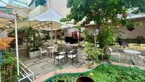 Un patio exterior con áreas de estar, una sección cubierta y una pequeña fuente de agua.