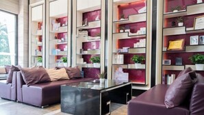 A modern living area with a sofa set, a glass coffee table, and built-in shelving with books and decorative items. - Lavande Hotel (Foshan Shunde Jinlong Metro Station) (Foshan)