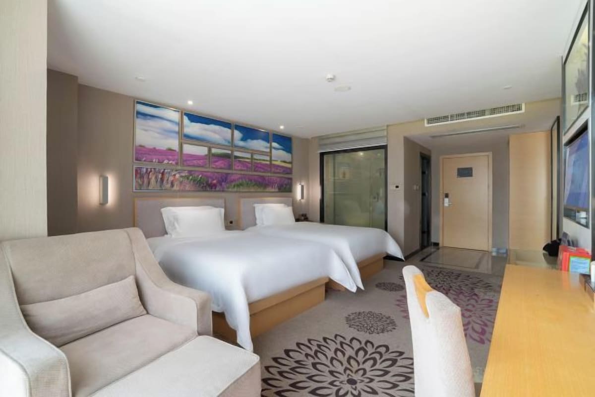 Una camera d'albergo con un letto, un divano, una scrivania e un quadro appeso al muro.