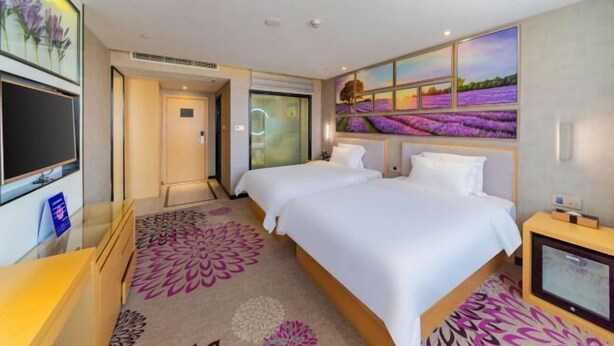 A hotel room with two beds, a TV, a desk, and a large window with a view of lavender fields. - Lavande Hotel (Foshan Shunde Jinlong Metro Station) (Foshan)