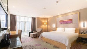 A hotel room with a large bed, a desk with a chair, a lamp, and a painting on the wall. - Lavande Hotel (Foshan Shunde Jinlong Metro Station) (Foshan)
