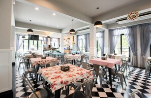 Ein Restaurant mit mehreren Tischen, Stühlen, einer Rezeption und einer Bar.