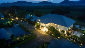 A large building with a flat roof, surrounded by greenery and a parking area. - Reindeer Park Resort (Nakhon Nayok)
