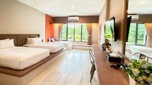 A hotel room with a large bed, a smaller bed, a desk with a chair, a TV, and a window with curtains. - Reindeer Park Resort (Nakhon Nayok)