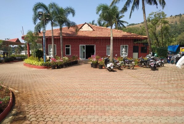A red-brick building with a tiled roof, surrounded by potted plants and parked motorcycles. - Whispering Woods Resort-lonavala (Lonavala)