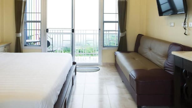A hotel room with a bed, a seating area, a television, and a balcony with a view. - Hotel Viewpoint Khao Koh (Khao Kho)