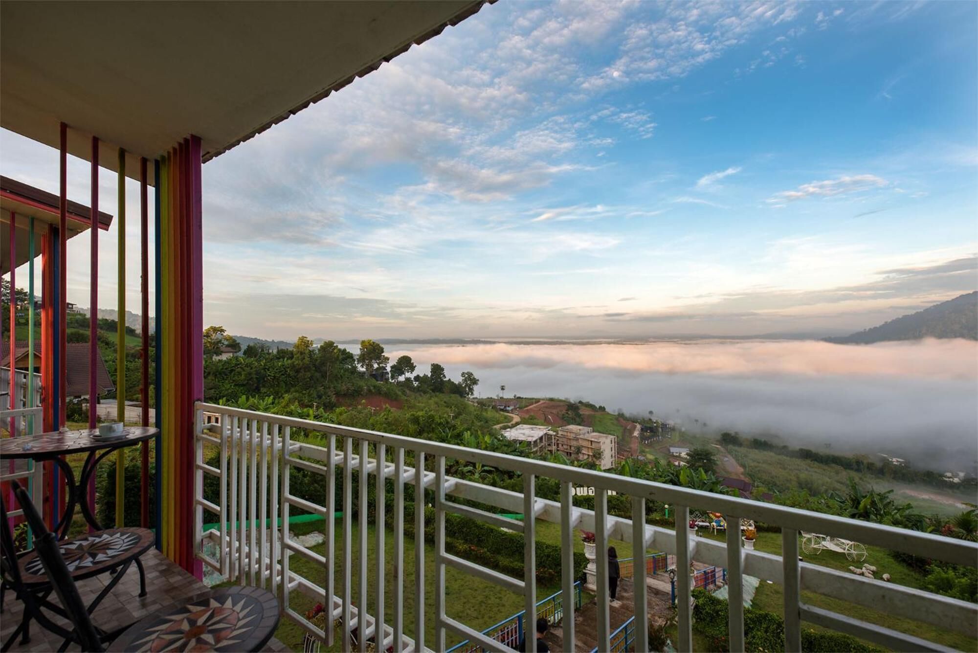 Un balcón con vistas a un valle y montañas cubiertas de niebla.