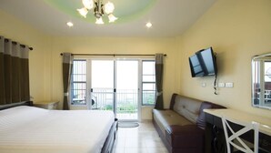 A hotel room with a bed, a desk, a chair, a television, and a balcony with curtains. - Hotel Viewpoint Khao Koh (Khao Kho)