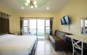 A hotel room with a bed, a desk, a chair, a television, and a balcony with curtains. - Hotel Viewpoint Khao Koh (Khao Kho)