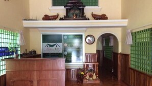 A reception area with a wooden reception desk, a wall-mounted sign, a clock, and a green-tinted window. - 139 Guest House (Phnom Penh)