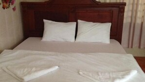 A neatly made bed with white linens and pillows, a wooden headboard, and a wooden bedside table. - 139 Guest House (Phnom Penh)