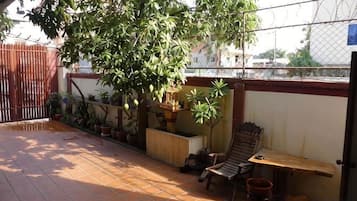 Um pátio com um banco de madeira, uma mesa pequena e plantas em vasos.