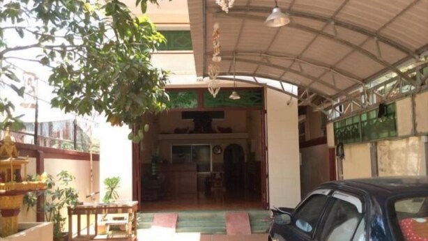 A covered entrance with a car parked outside, a small table, and a decorative fountain. - 139 Guest House (Phnom Penh)