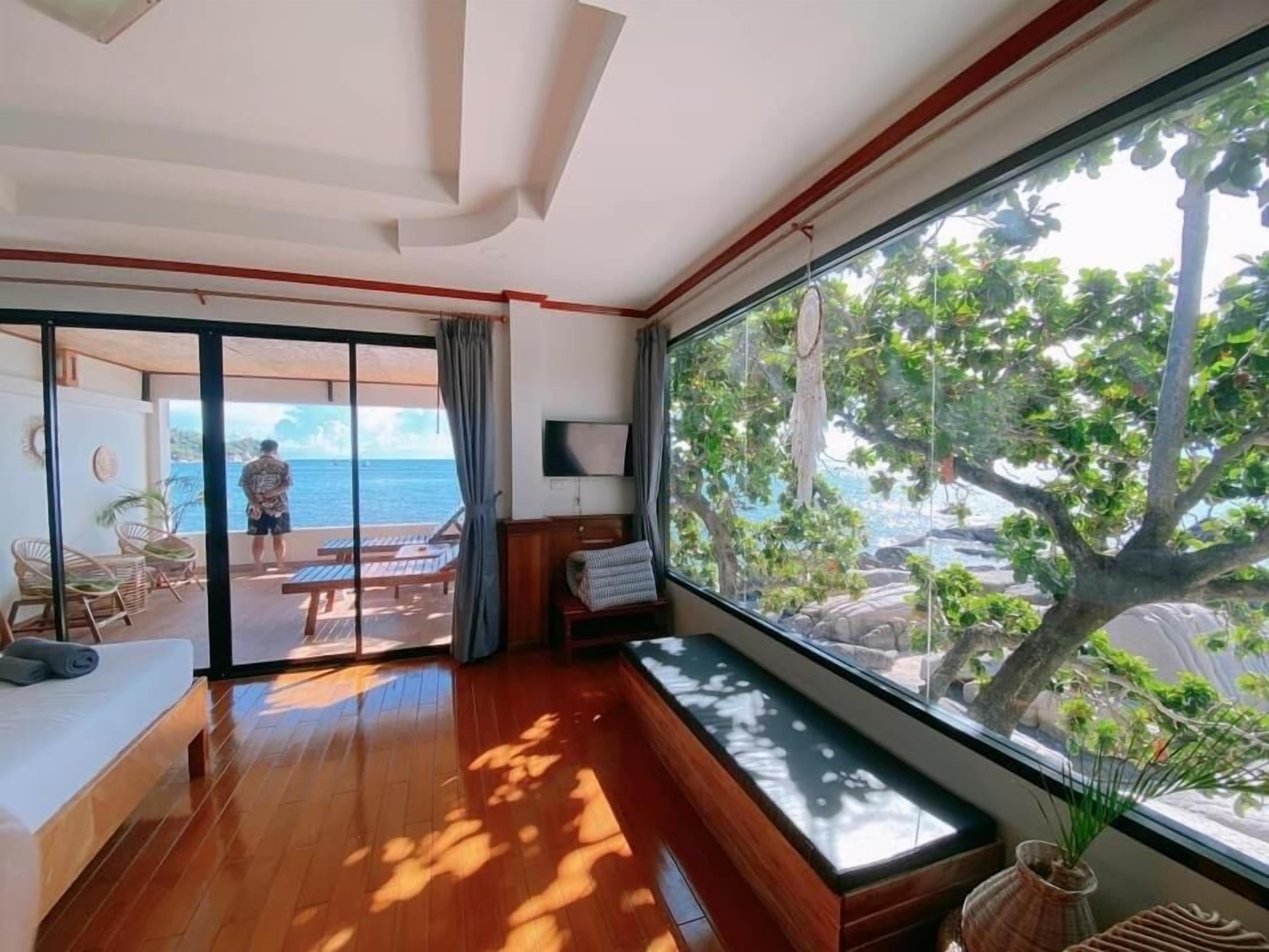 Et moderne hotelværelse med en stor skydedør, der fører ud til en balkon med havudsigt.