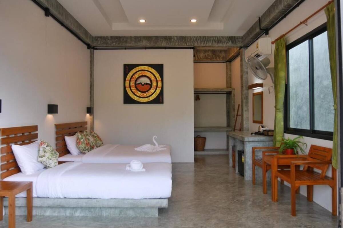 Een hotelkamer met twee bedden, een zithoek en een groot raam.