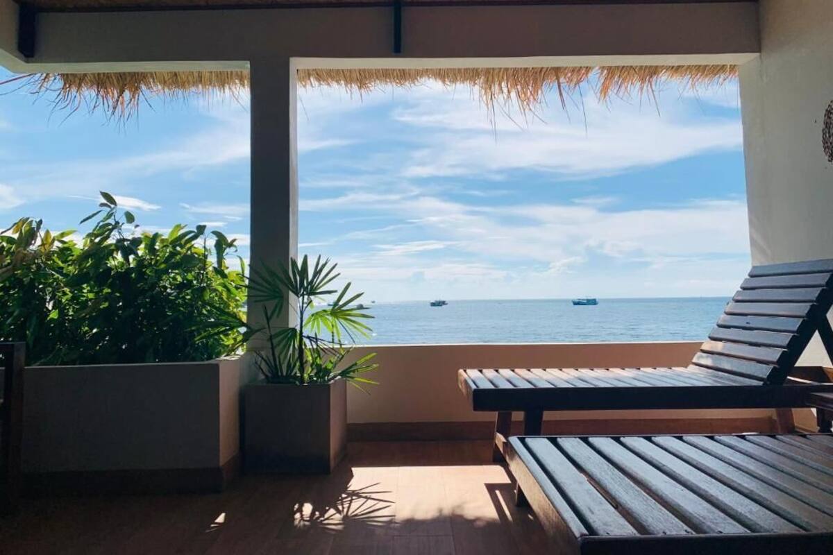 Een balkon met uitzicht op zee, een houten bankje en potplanten.
