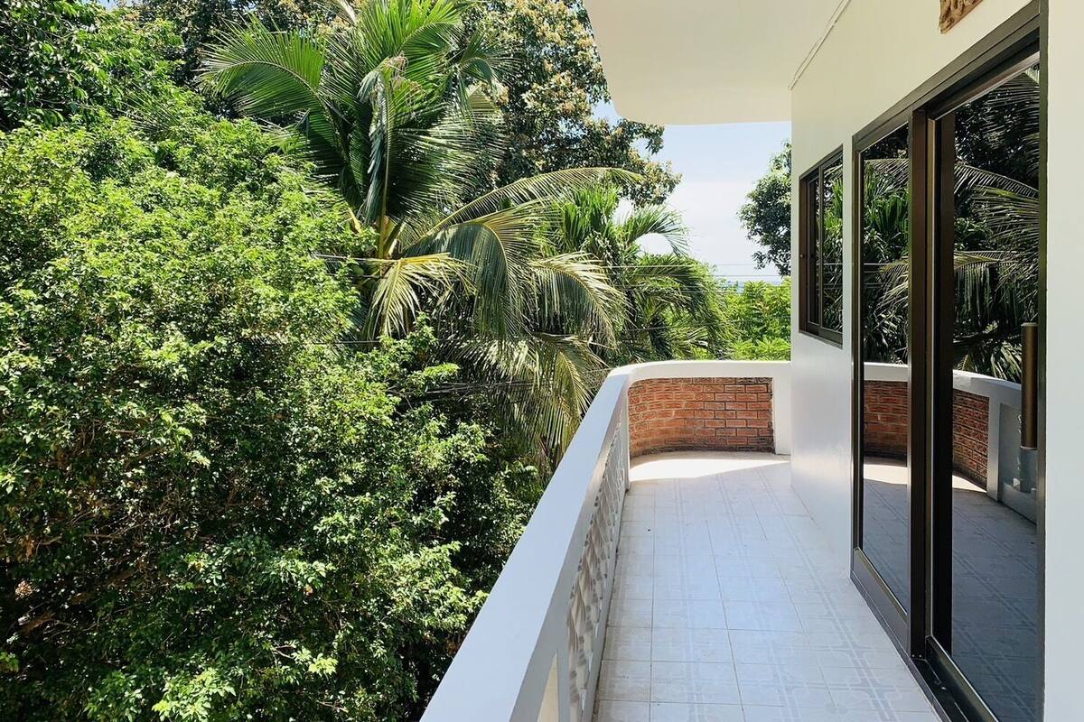 Een balkon met uitzicht op weelderige begroeiing en een bakstenen muur.