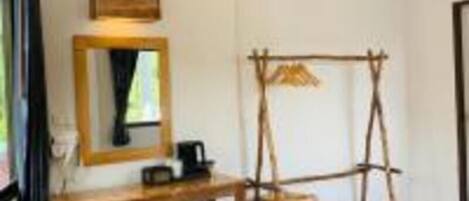 Una habitación con un escritorio de madera, un refrigerador pequeño, una silla colgante y un espejo en la pared.