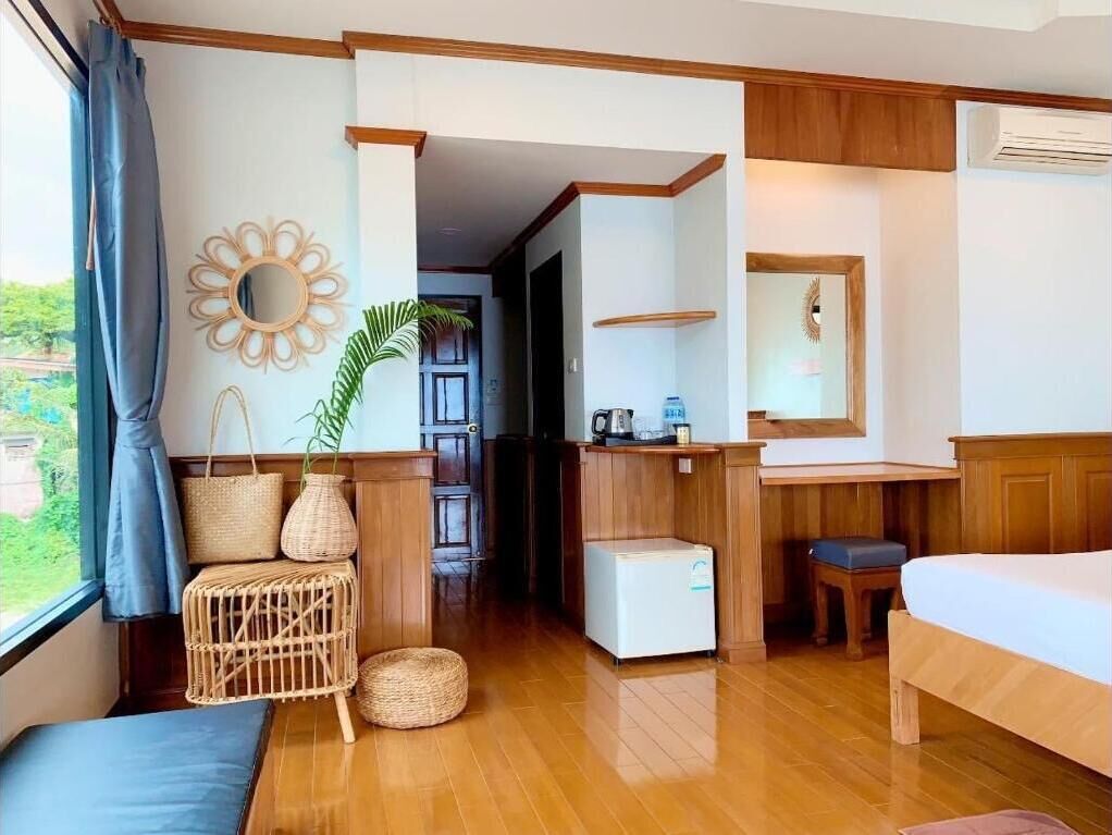 A hotel room with a bed, a small desk, a chair, a mirror, and a window with curtains.