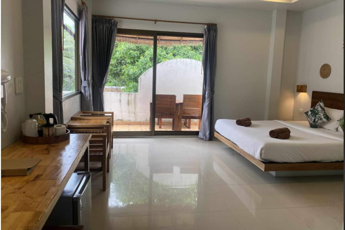 Een slaapkamer met een bed, een bureau en uitzicht op groen.