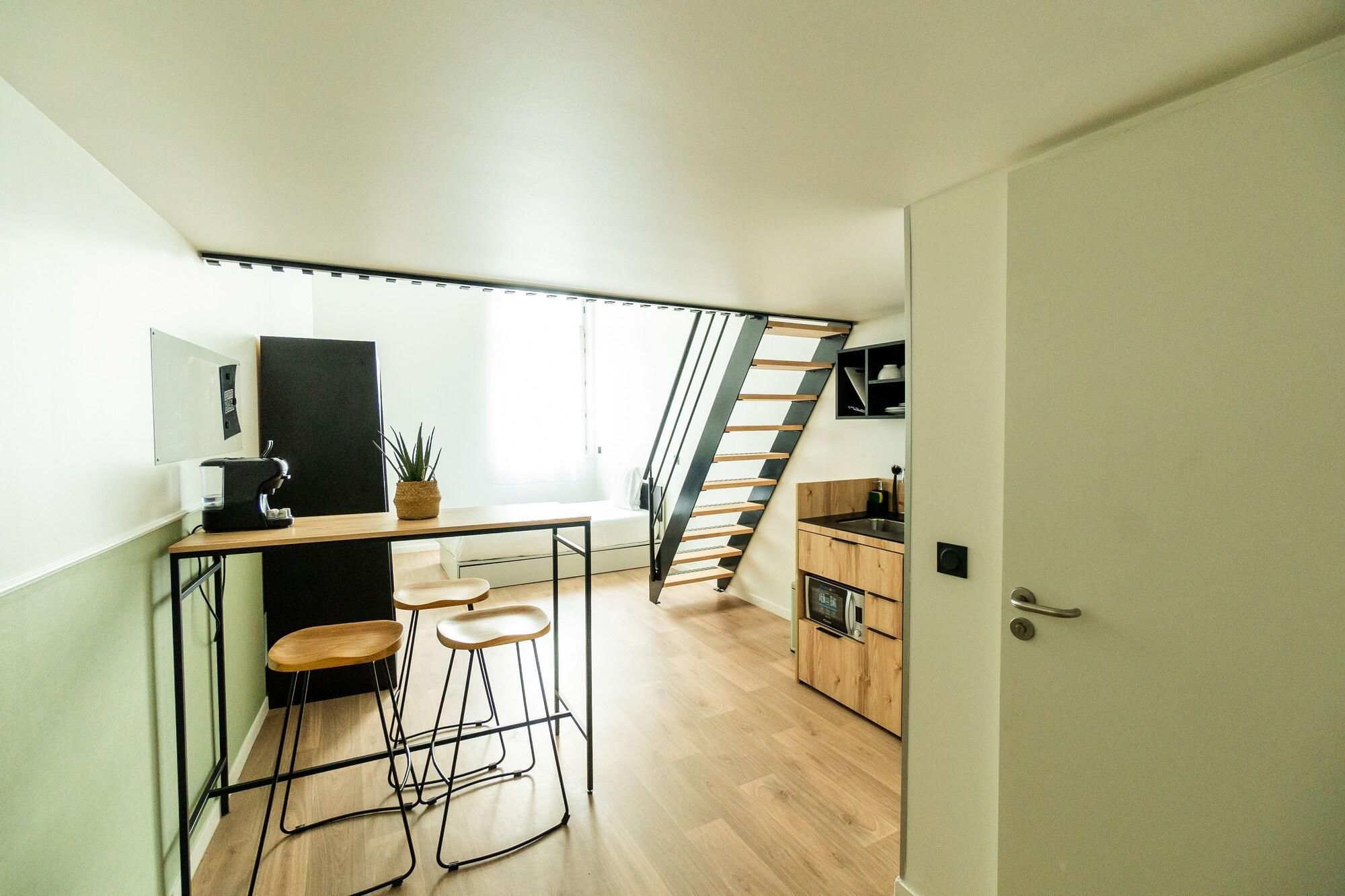 Eine kleine Küche mit einer Holzausziehtheke, Barhocker und einer Treppe zu einer oberen Ebene.