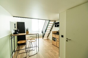 Eine kleine Küche mit einer Holzausziehtheke, Barhocker und einer Treppe zu einer oberen Ebene.