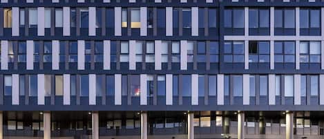 Un edificio de varios pisos con un diseño arquitectónico moderno, caracterizado por una serie de líneas verticales y horizontales que forman un patrón tipo cuadrícula.