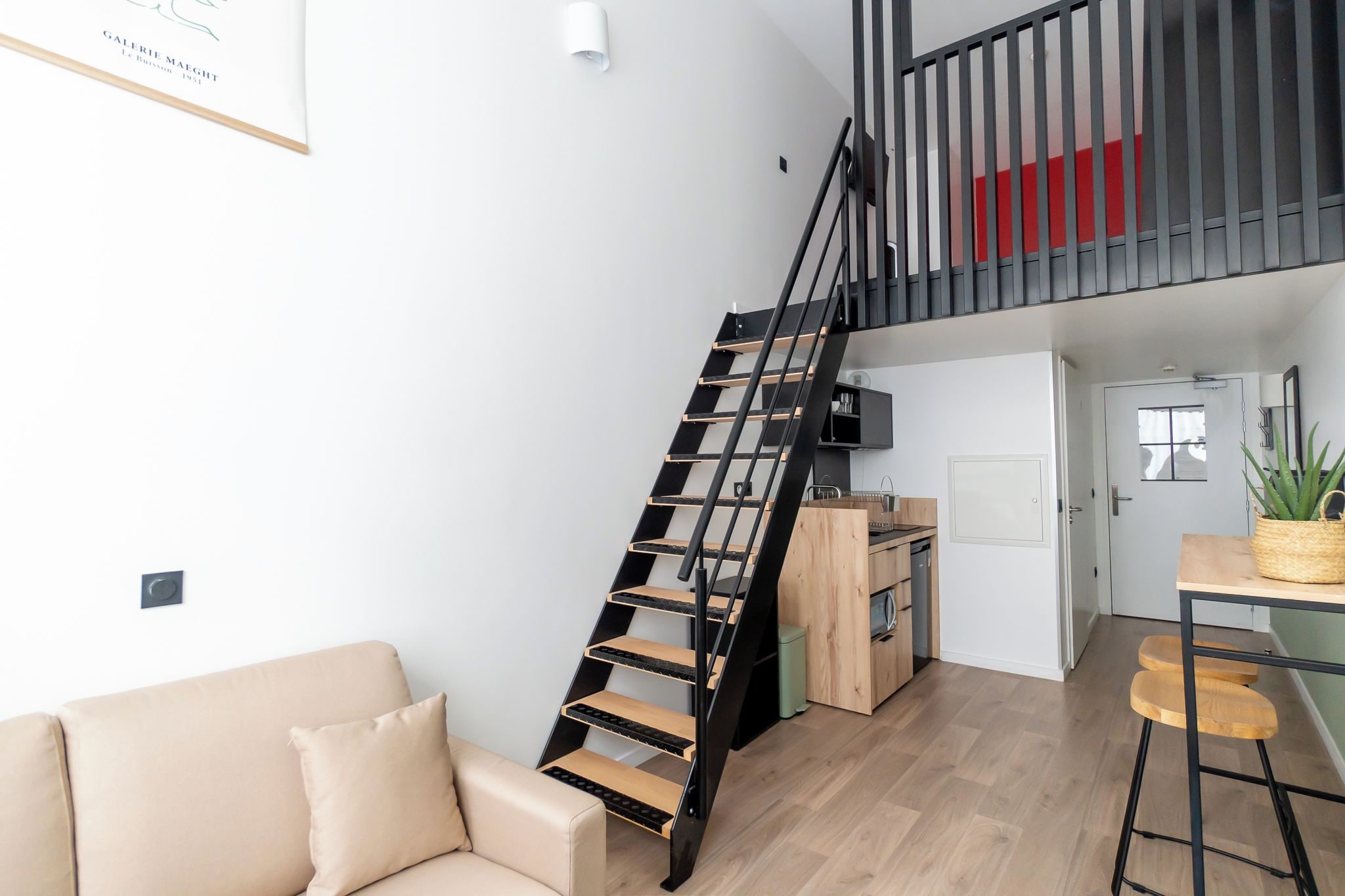 Un appartement moderne doté d’un escalier en colimaçon noir, d’une kitchenette, d’un coin repas et d’un salon avec un canapé.