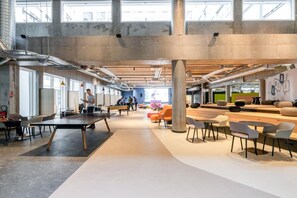 A spacious, modern office with high ceilings, exposed ductwork, and large windows. - Ecla Massy Palaiseau (Palaiseau)