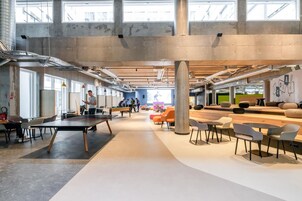 Una oficina amplia y moderna con techos altos, conductos expuestos y ventanas grandes.