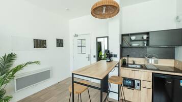 Una cocina moderna con una isla de madera, taburetes de bar, una cafetera y un lavavajillas integrado.
