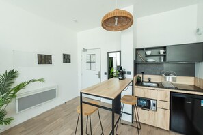 Eine moderne Küche mit einer Holzeile, Barhocker, einer Kaffeemaschine und einem eingebauten Geschirrspüler.