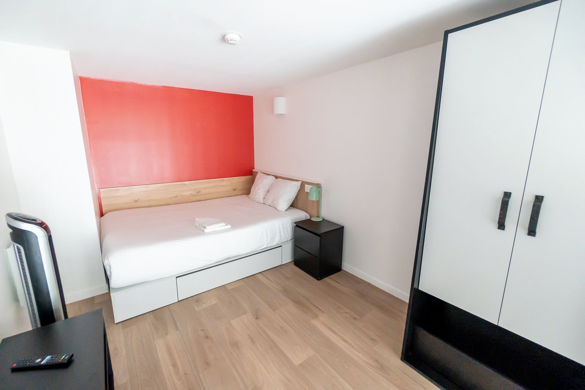 A bedroom with a bed, bedside table, wardrobe, and a heater.