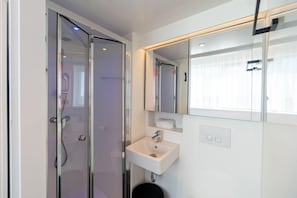 A modern bathroom with a glass shower enclosure, a white sink, and a large mirror. - Ecla Massy Palaiseau (Palaiseau)