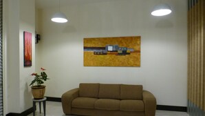 Una habitación amplia con un sofá marrón, una planta en maceta y un cuadro en la pared.