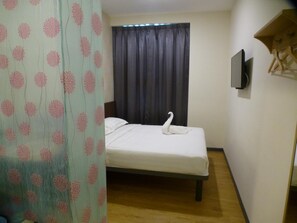 A single bed with a swan-shaped pillow, a television on the wall, and a curtain with a floral pattern. - Hotel 138 @ Bestari (Shah Alam)