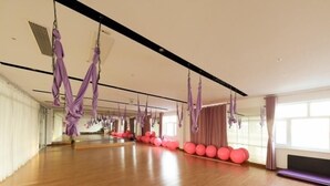 A spacious room with a wooden floor, purple aerial yoga hammocks, and a row of pink exercise balls. - Greentree Inn Tangshan Caofeidian District Nanbao Development Zone (Tangshan)